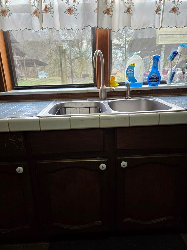 details with tile counters, a sink, and dark brown cabinetry