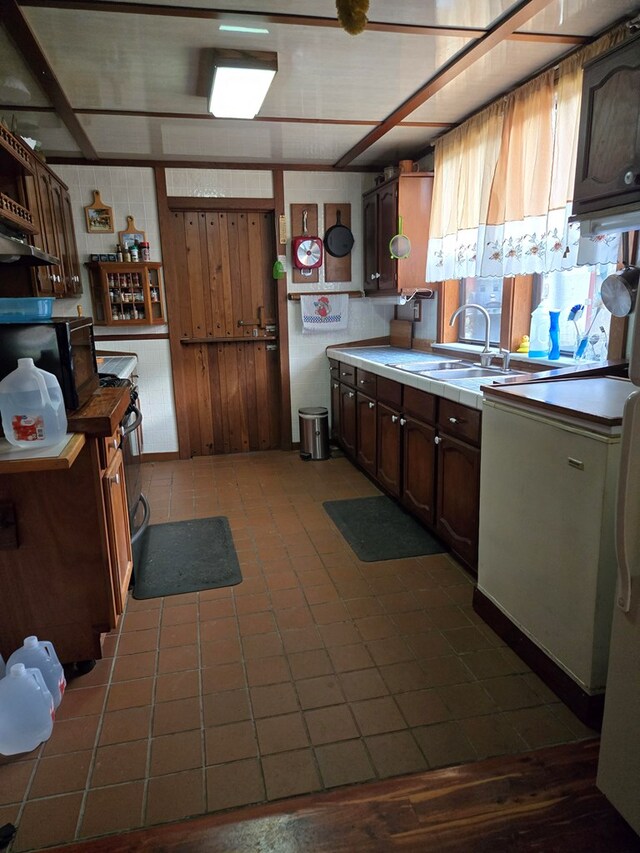 kitchen featuring black microwave, light countertops, wood walls, and a sink