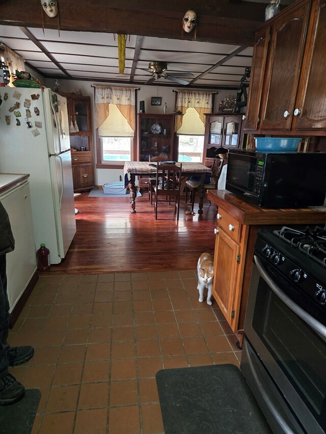 kitchen featuring dark wood-style flooring, gas stove, freestanding refrigerator, black microwave, and fridge