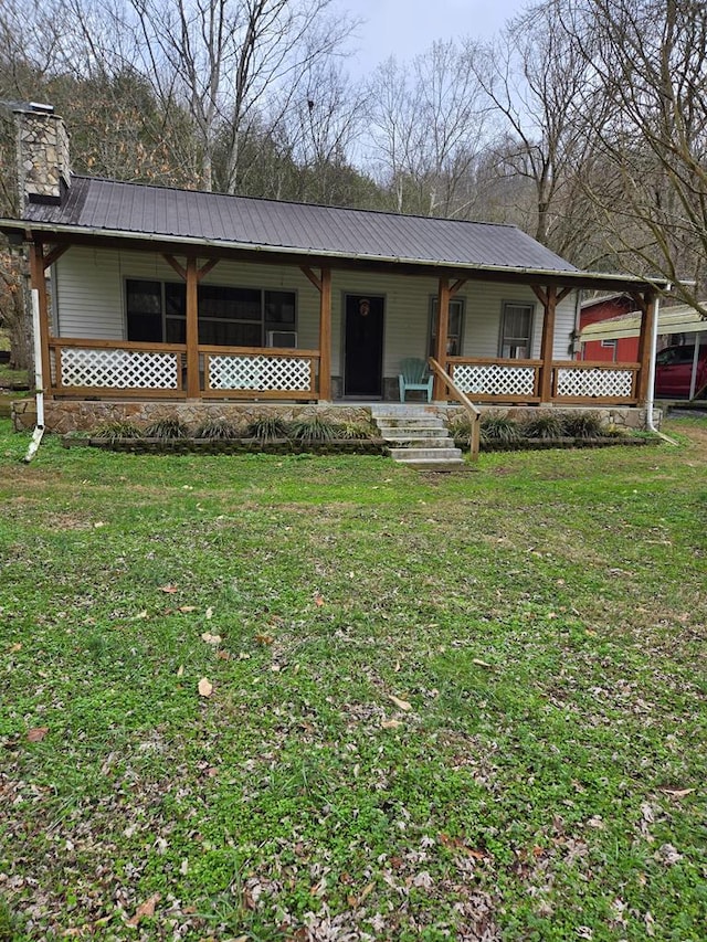 view of front facade with metal roof, a front lawn, a chimney, and a porch