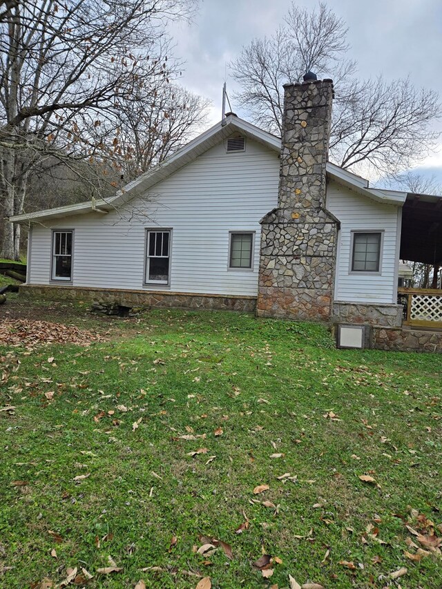 rear view of house featuring a chimney and a lawn