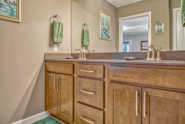 bathroom featuring a sink, baseboards, and double vanity