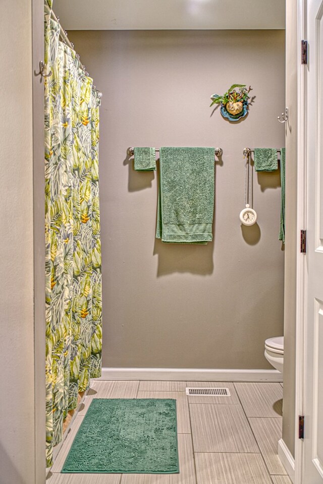 bathroom featuring toilet, visible vents, and baseboards