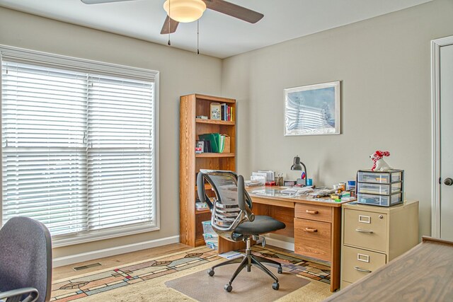 home office featuring light wood-type flooring, visible vents, ceiling fan, and baseboards