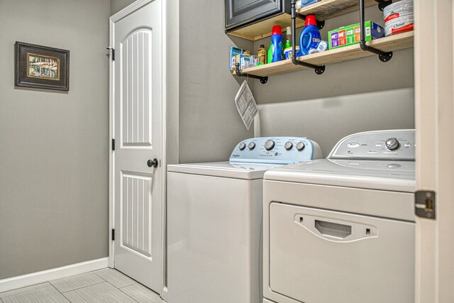 clothes washing area featuring separate washer and dryer, cabinet space, and baseboards