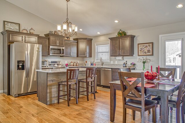 kitchen with light wood-style floors, a center island, stainless steel appliances, and decorative light fixtures