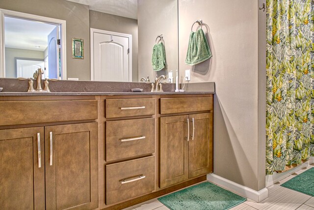 bathroom featuring double vanity, a sink, and baseboards