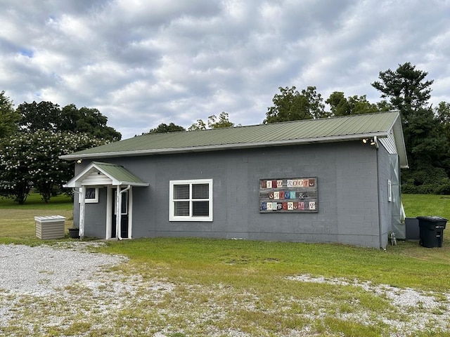 exterior space with metal roof, a lawn, and concrete block siding