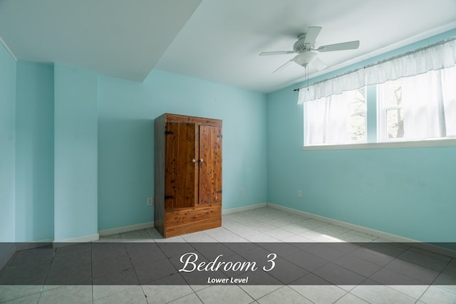 spare room with baseboards, a ceiling fan, and tile patterned floors