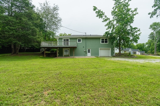 back of house featuring an attached garage, a lawn, driveway, and a wooden deck