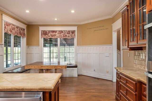 kitchen featuring tile counters, brown cabinets, glass insert cabinets, and dark wood-style floors