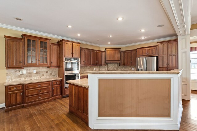 kitchen with stainless steel appliances, dark wood-type flooring, brown cabinetry, and a kitchen island