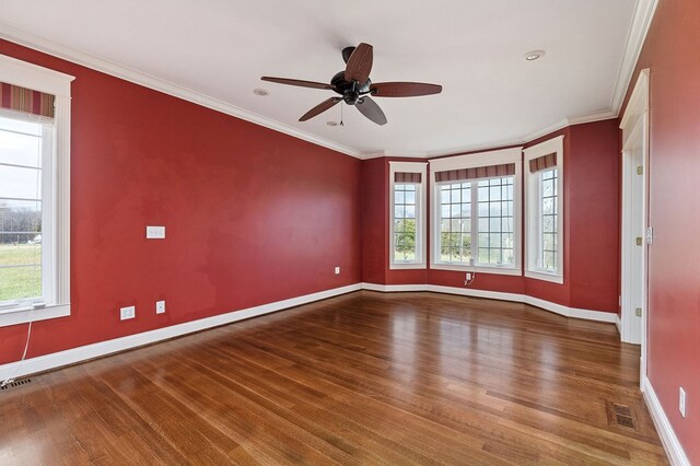 empty room with ornamental molding, wood finished floors, and visible vents