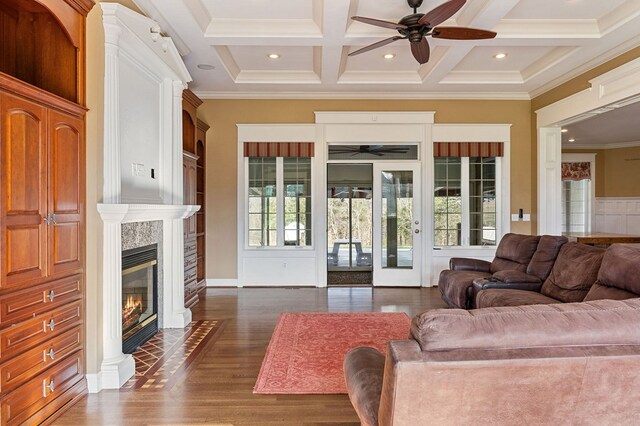 living area with dark wood-type flooring, coffered ceiling, a fireplace with flush hearth, ornamental molding, and beamed ceiling