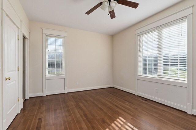 unfurnished bedroom with dark wood-style flooring, a ceiling fan, and baseboards