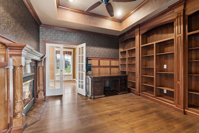 unfurnished living room with wallpapered walls, ceiling fan, ornamental molding, wood finished floors, and french doors