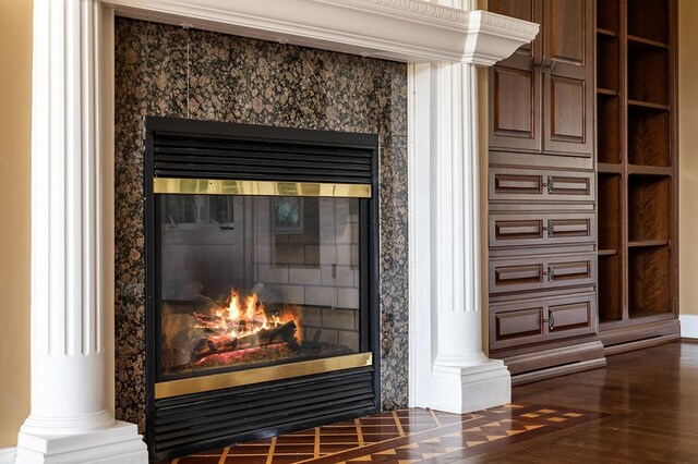 details featuring ornate columns, wood finished floors, and a high end fireplace