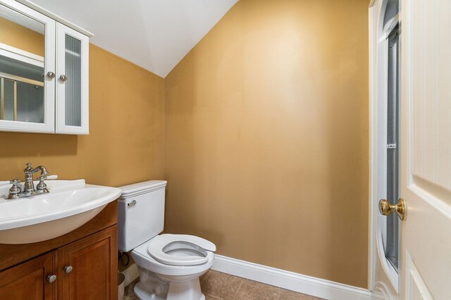 bathroom with baseboards, lofted ceiling, toilet, tile patterned floors, and vanity