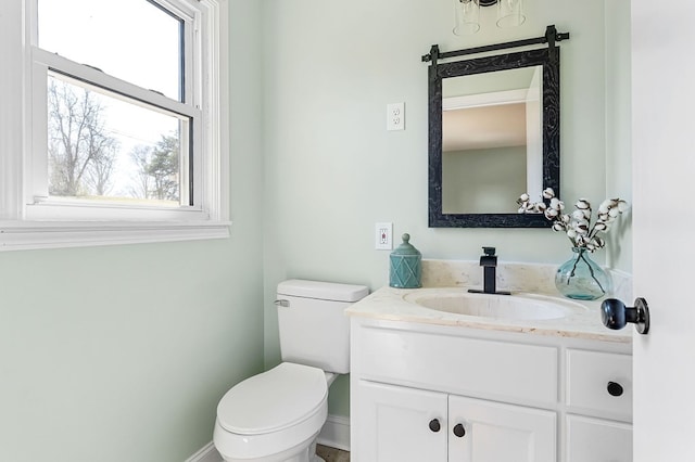 bathroom with toilet, vanity, and baseboards