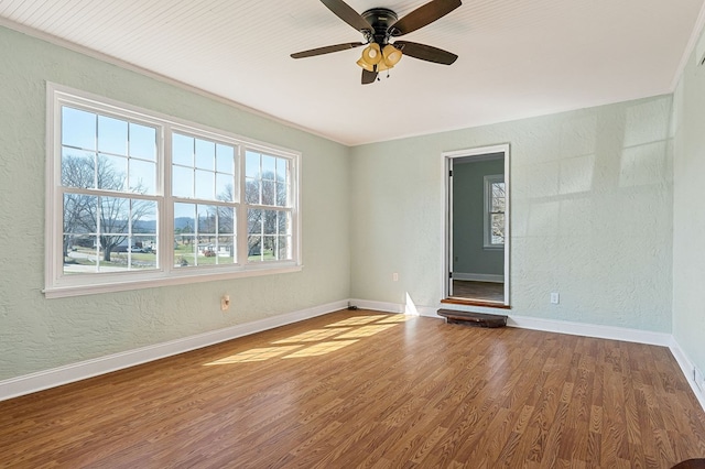 spare room with baseboards, wood finished floors, a ceiling fan, and a textured wall