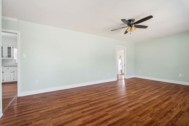 empty room featuring dark wood-style floors, baseboards, and ceiling fan