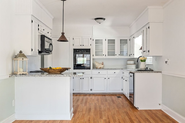 kitchen featuring black appliances, light wood-style flooring, white cabinets, and a sink