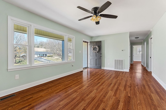 unfurnished living room with visible vents, a ceiling fan, baseboards, and wood finished floors