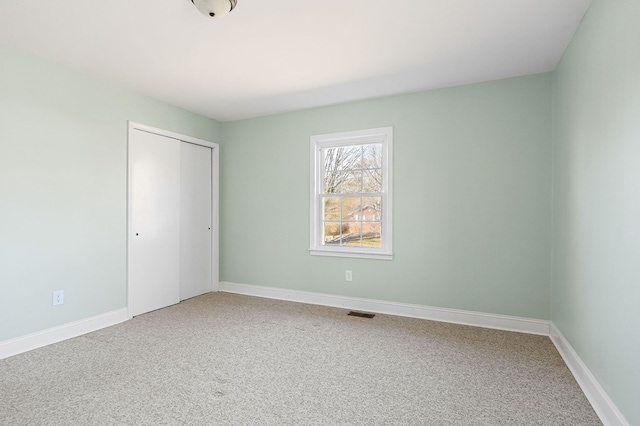 unfurnished bedroom featuring a closet, carpet flooring, visible vents, and baseboards