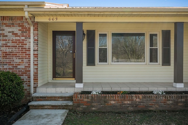 property entrance featuring a porch and brick siding