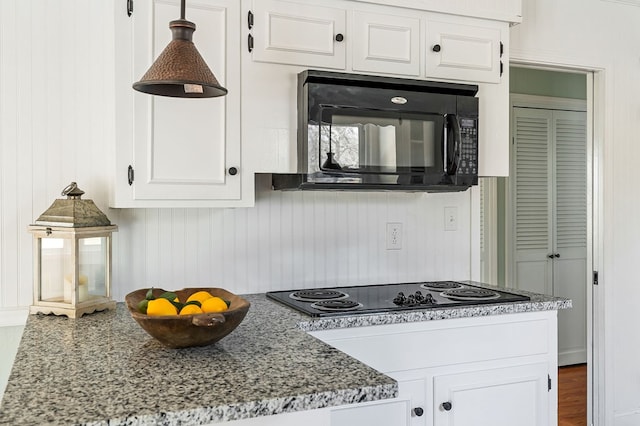 kitchen with light stone countertops, black appliances, and white cabinetry