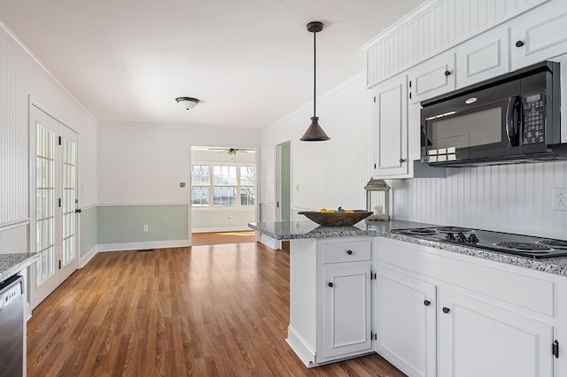 kitchen with a peninsula, wood finished floors, hanging light fixtures, white cabinets, and black appliances