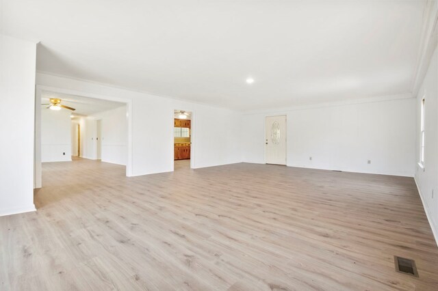 empty room featuring light wood-style flooring, crown molding, visible vents, and a ceiling fan