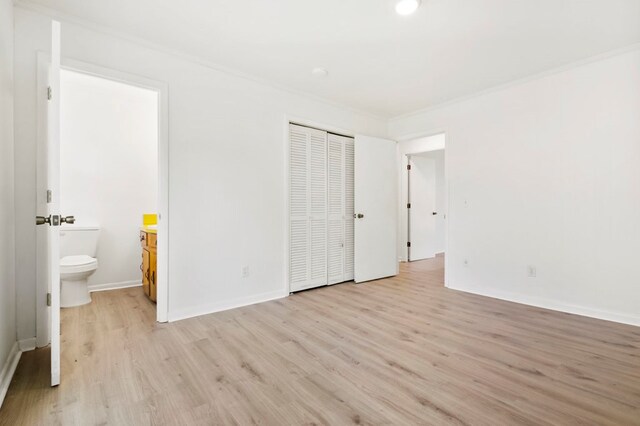 unfurnished bedroom featuring light wood-type flooring, a closet, and crown molding