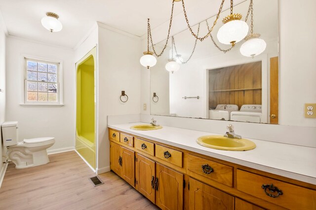 ensuite bathroom featuring double vanity, visible vents, a sink, and separate washer and dryer