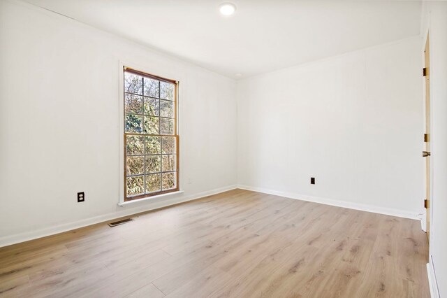 unfurnished room with light wood-style floors, visible vents, and baseboards