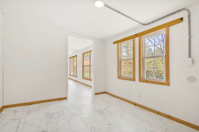 spare room with marble finish floor and baseboards