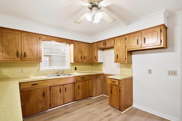 kitchen featuring a sink, light countertops, light wood-type flooring, brown cabinets, and decorative backsplash