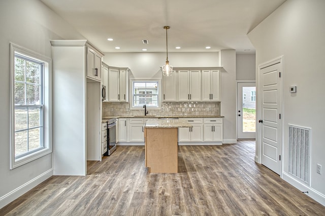 kitchen featuring visible vents, decorative backsplash, dark wood-style floors, decorative light fixtures, and a center island