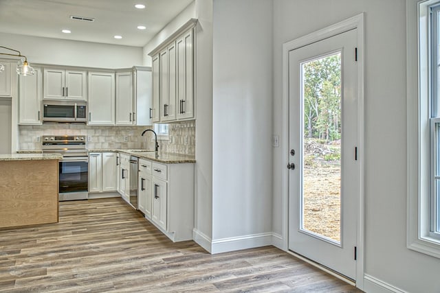 kitchen with light stone countertops, tasteful backsplash, appliances with stainless steel finishes, and a sink