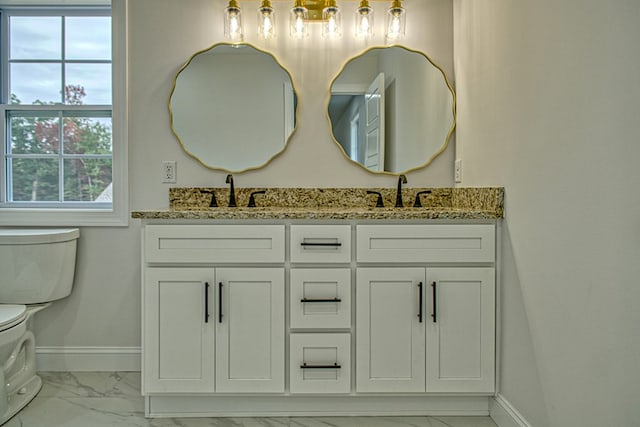 bathroom with toilet, marble finish floor, baseboards, and a sink