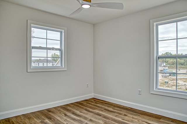 empty room featuring a ceiling fan, baseboards, a wealth of natural light, and wood finished floors