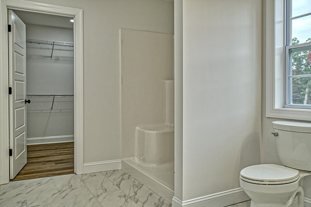 full bathroom featuring marble finish floor, a spacious closet, and baseboards