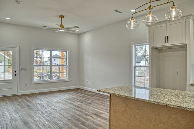 kitchen with light stone counters, white cabinetry, plenty of natural light, and visible vents