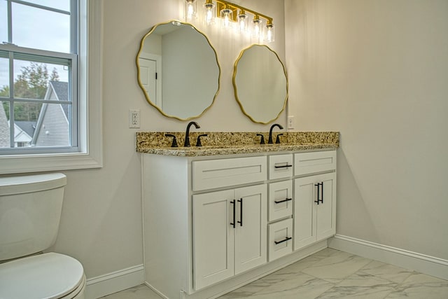 bathroom with double vanity, marble finish floor, baseboards, and a sink