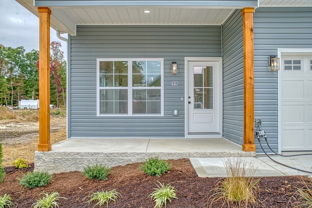 doorway to property with covered porch and an attached garage