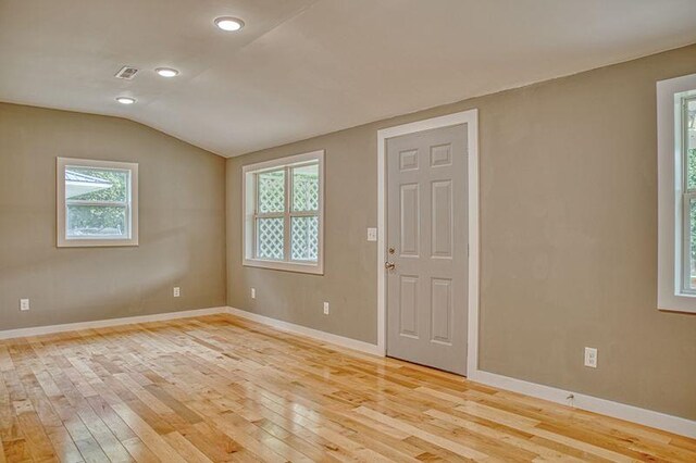 unfurnished room with light wood-type flooring, baseboards, and vaulted ceiling