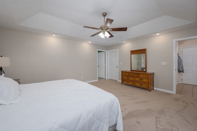 bedroom with light carpet, ceiling fan, baseboards, and a raised ceiling