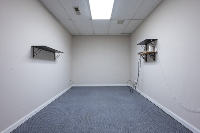 carpeted empty room featuring visible vents, a paneled ceiling, and baseboards