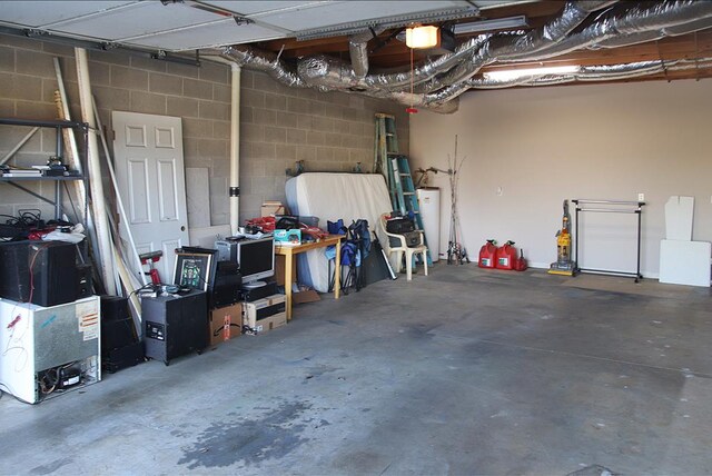 garage featuring a garage door opener, concrete block wall, and gas water heater