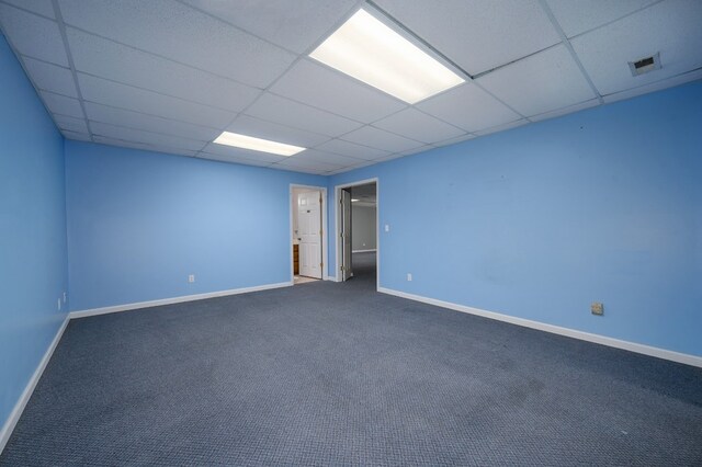 empty room featuring carpet floors, baseboards, visible vents, and a paneled ceiling